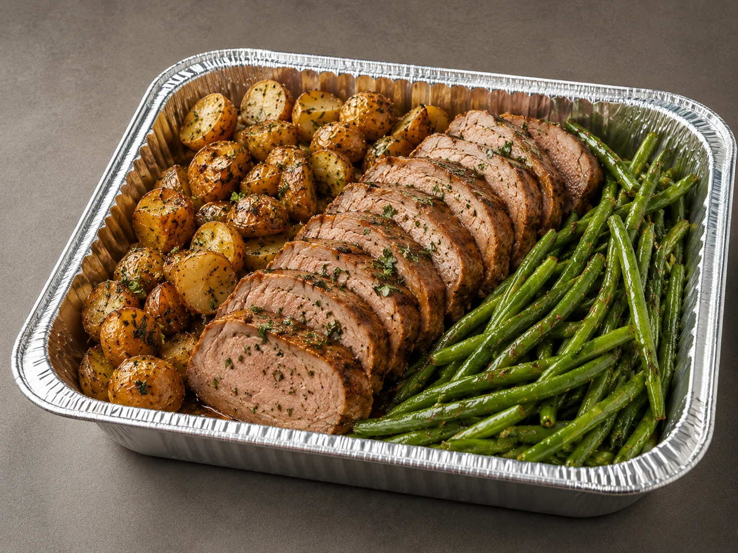 Pork Tenderloin Family Bundle with sliced roasted pork, potatoes and green beans in a half-size aluminum tray