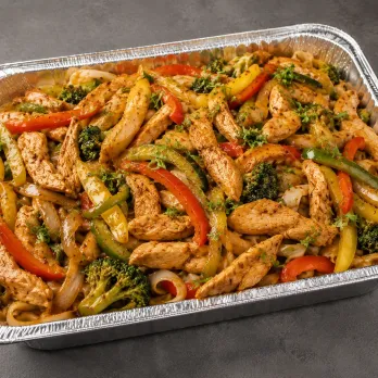 Chicken Stir Fry Family Bundle with chicken, peppers, broccoli, onions and rice noodles in an aluminum tray