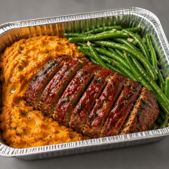 Turkey Meatloaf Family Bundle with sliced glazed turkey meatloaf, mashed sweet potatoes and green beans in an aluminum tray