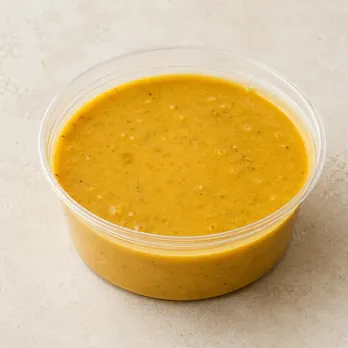 Almond Coconut Curry in a clear takeout sauce cup.