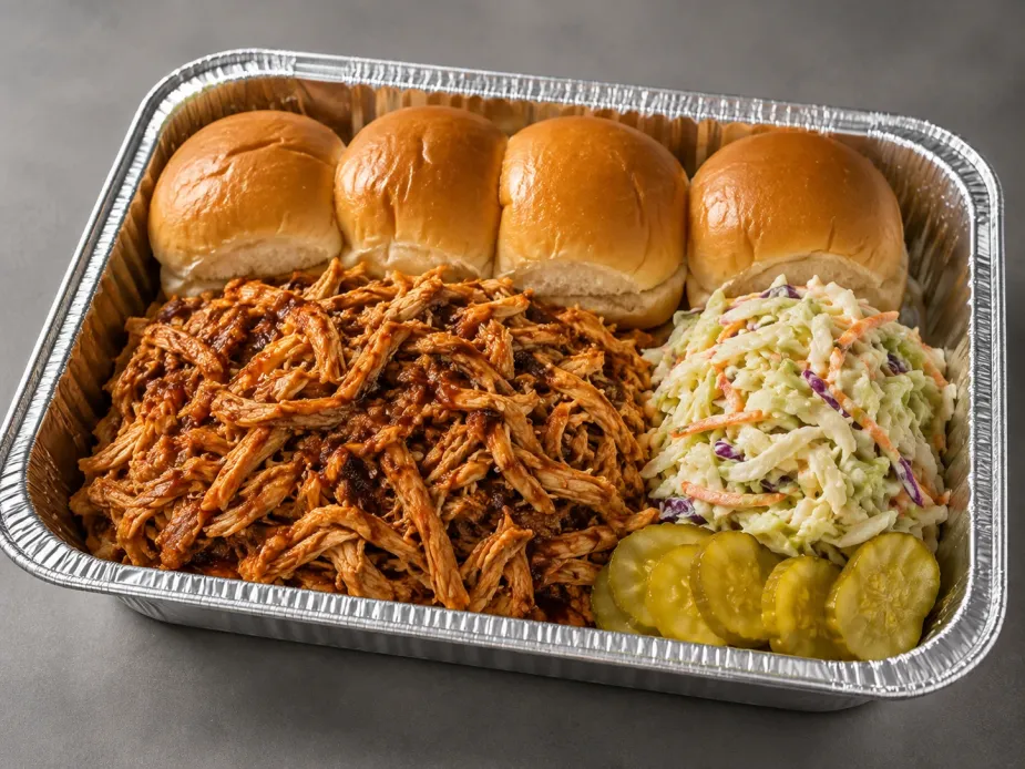BBQ Pulled Chicken Sliders Family Bundle with saucy pulled chicken, slider rolls, coleslaw and roasted sweet potato wedges in an aluminum tray