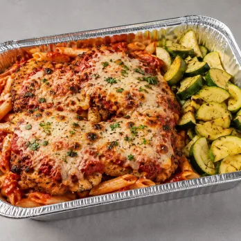 Chicken Parmesan Pasta Family Bundle in an aluminum tray with breaded chicken, marinara, mozzarella, pasta and zucchini