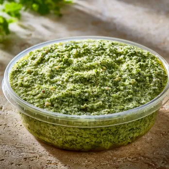 Homemade Pesto sold by the ounce in a black meal-prep container.