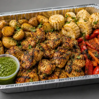 Peruvian Chicken Anticuchos Family Bundle with anticucho-style marinated chicken, roasted potatoes, corn and peppers in an aluminum tray