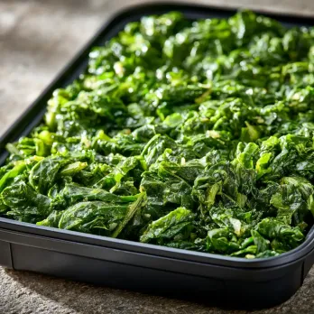 Tuscan Greens sold by the ounce in a black meal-prep container.