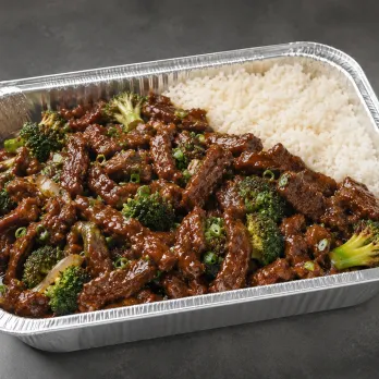 Mongolian Beef Family Bundle with glossy sauced beef, coconut rice and snap peas in a half-size aluminum tray