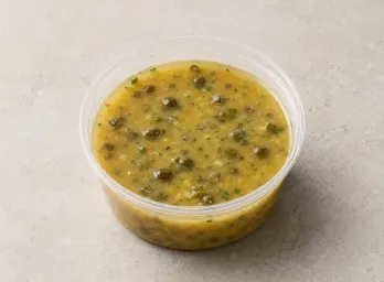 Lemon-Caper Picatta in a clear takeout sauce cup.