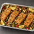 Mediterranean Salmon Family Bundle with herb-roasted salmon, lemon couscous, cucumber-tomato salad and tahini in an aluminum family tray