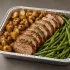 Pork Tenderloin Family Bundle with sliced roasted pork, potatoes and green beans in a half-size aluminum tray