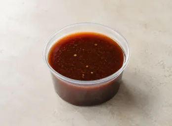 THK Mongolian Sauce in a clear takeout sauce cup.