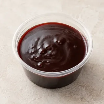 Malbec-Hibiscus Demiglace in a clear takeout sauce cup.