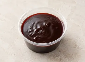 Malbec-Hibiscus Demiglace in a clear takeout sauce cup.