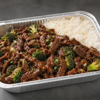 Mongolian Beef Family Bundle with glossy sauced beef, coconut rice and snap peas in a half-size aluminum tray
