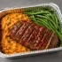 Turkey Meatloaf Family Bundle with sliced glazed turkey meatloaf, mashed sweet potatoes and green beans in an aluminum tray