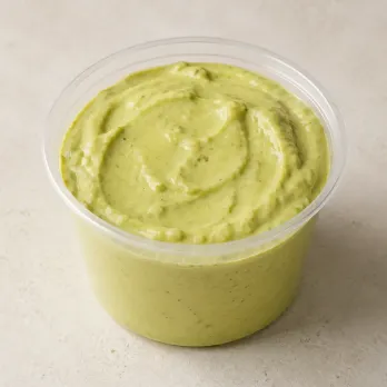 Avocado aioli in a clear takeout sauce cup.
